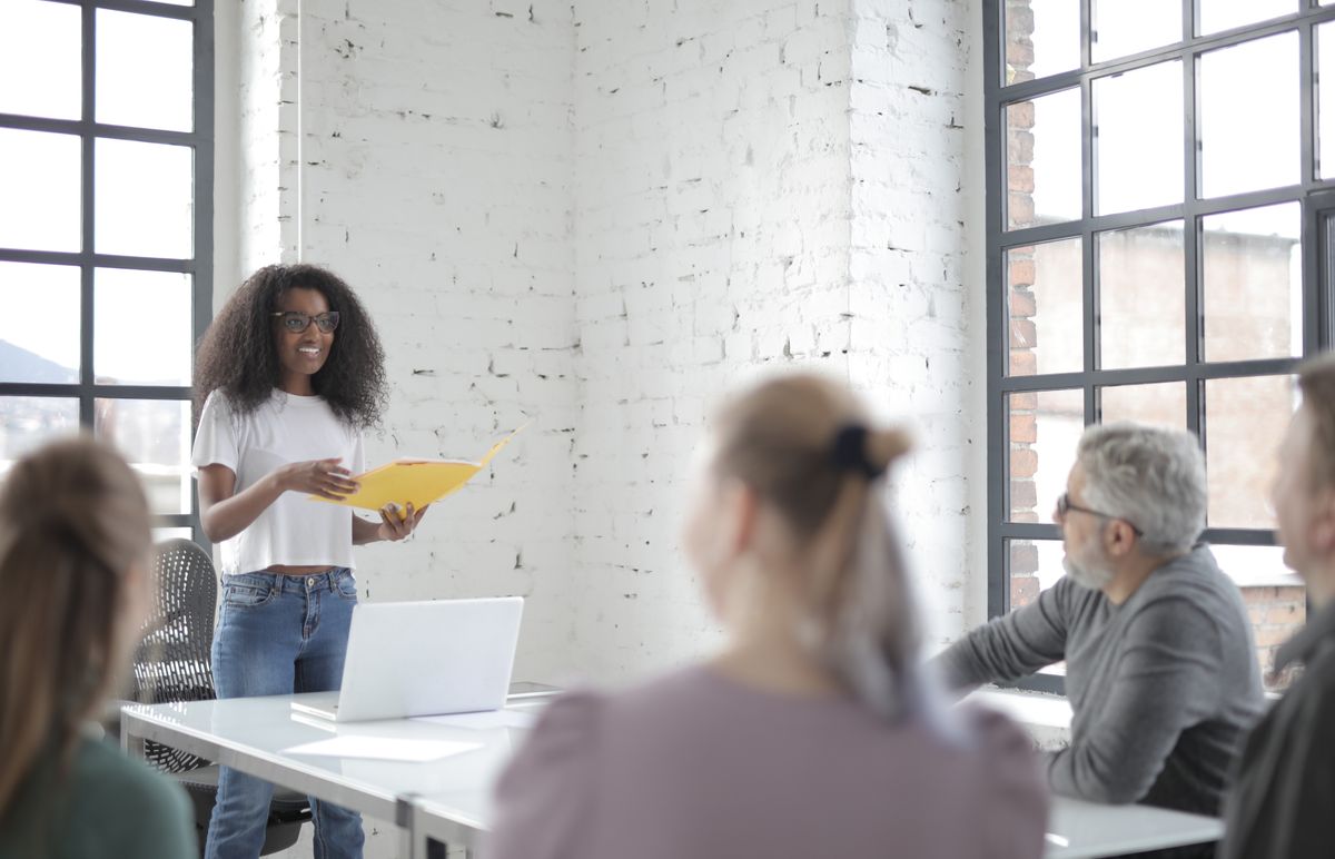 Mulher negra apresenta ideias a uma equipe em reunião